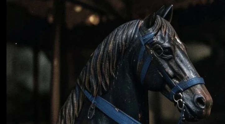 Close-up of a dark wooden horse with a weathered blue rein
